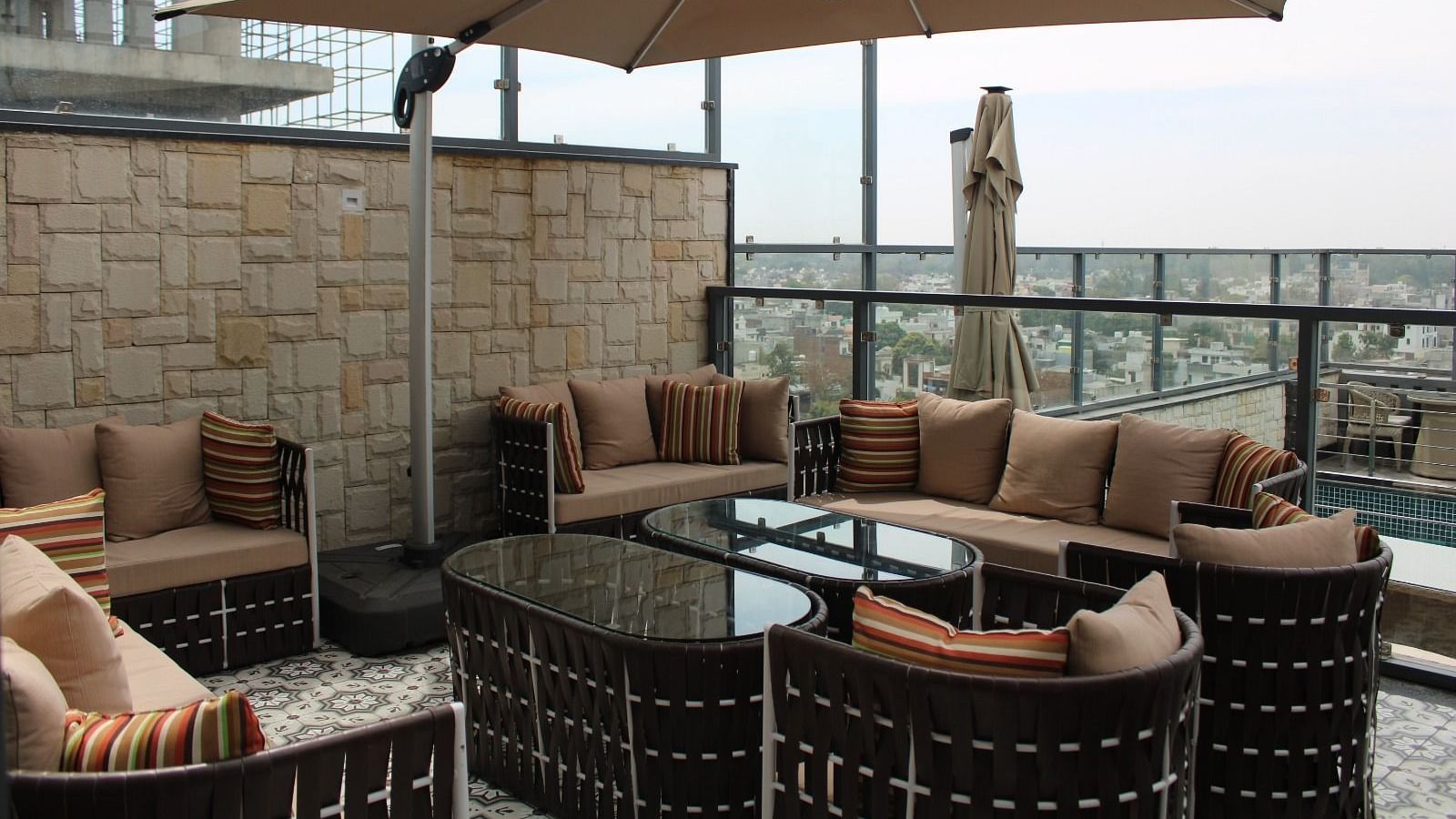 Rooftop lounge featuring sofas, pillows, and a patio offering stunning city views at BluSalzz Residence, Amritsar